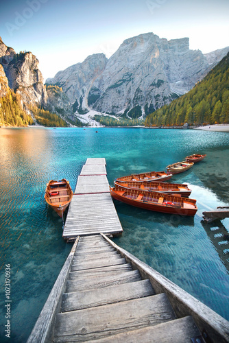 Fototapeta Naklejka Na Ścianę i Meble -  idyllic wooden pier with rustic wooden boats on a blue mountain lake surrounded by unique mountains
