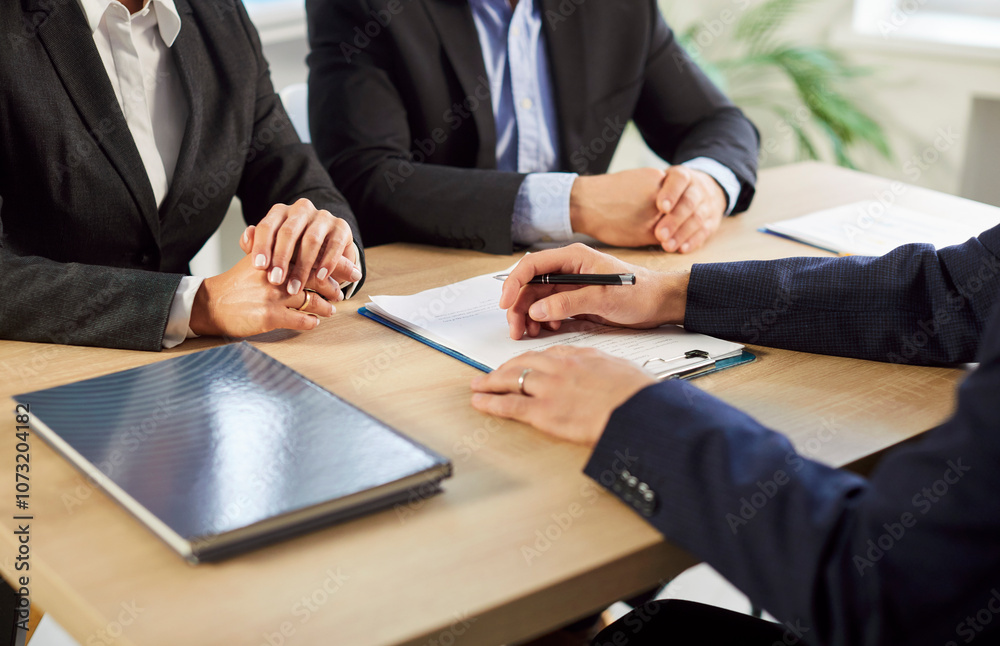 Close up of couple sitting at desk having consultation with man realtor or financial advisor in office. Insurance agent consulting man and woman in office going to sign a business contract.