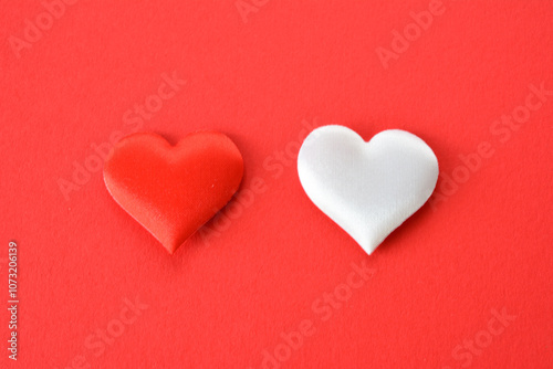 red and white silk hearts isolated on red background close up