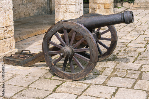 A fortress cast-iron cannon in an ancient fortress. Ancient weapons that fired cast-iron balls. Smooth bore cast iron cannon mounted on a wooden carriage.