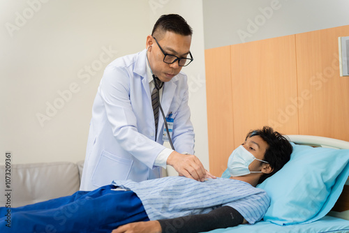 Asian health care professional conducts a medical yearly checkup examination, patient male lie down for observations, patient care services with specialist doctor using a stethoscope in clinic