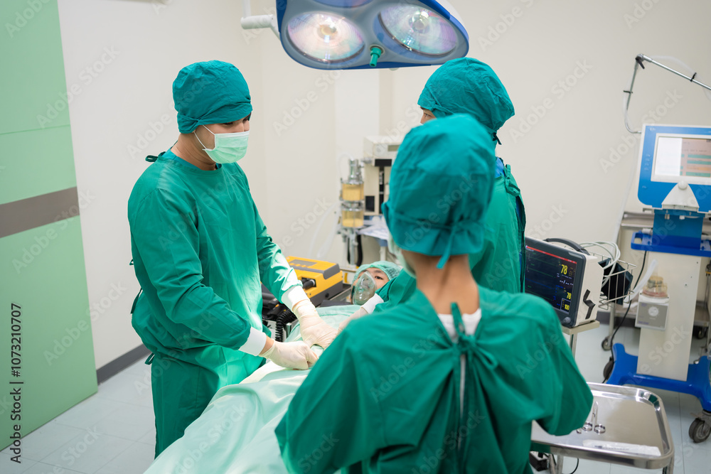 Group of surgical team in green coats ready for a patient man in operating room. Asian doctors and nurses focus on medical healthcare procedures, emphasizing teamwork efficiency in a modern hospital Group of surgical team in green coats ready for a patient man in operating room. Asian doctors and nurses focus on medical healthcare procedures, emphasizing teamwork efficiency in a modern hospital