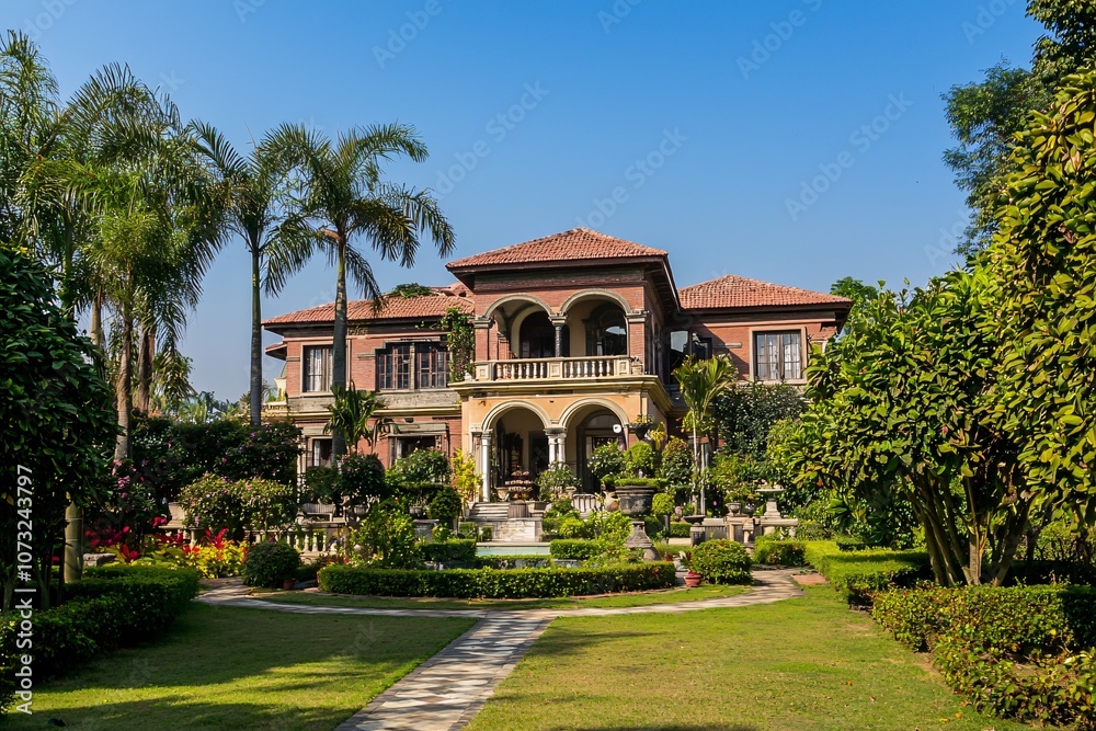 Fototapeta premium An opulent estate nestled among verdant gardens epitomizes sophistication and grandeur beneath a pristine azure sky.