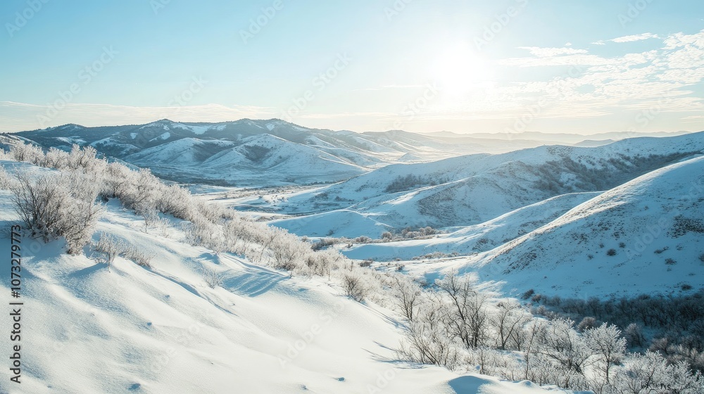 Fototapeta premium Snow-covered hills and mountains with a clear blue sky above and soft sunlight shining down