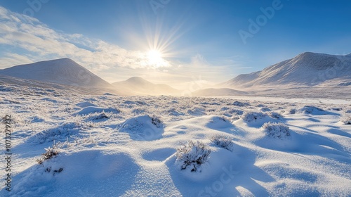 Snow-covered hills and mountains with a clear blue sky above and soft sunlight shining down