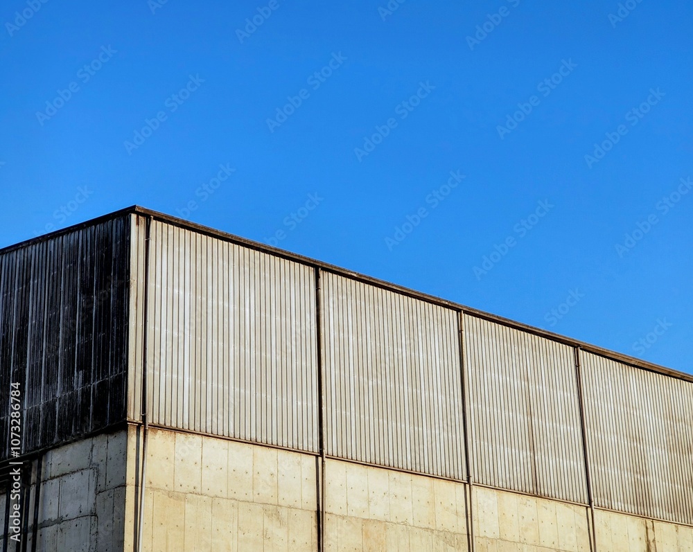 Fototapeta premium Aluminum corrugated industrial warehouse metal wall surface building on against blue sky background