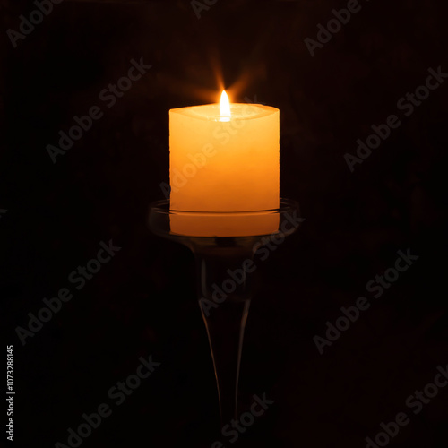 Burning candle on a glass base on a black background. photo