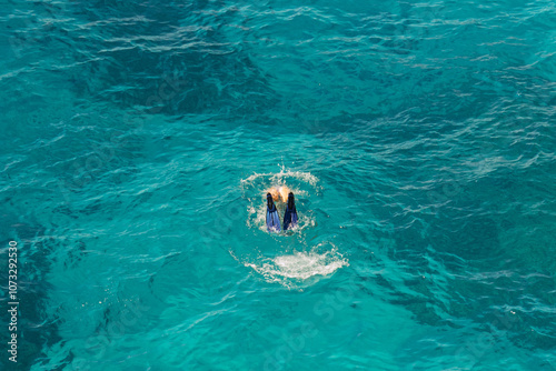 A lone man diving with fins in crystal-clear turquoise water, Ionian Sea, Himare, Albania, summer, filikuri beach