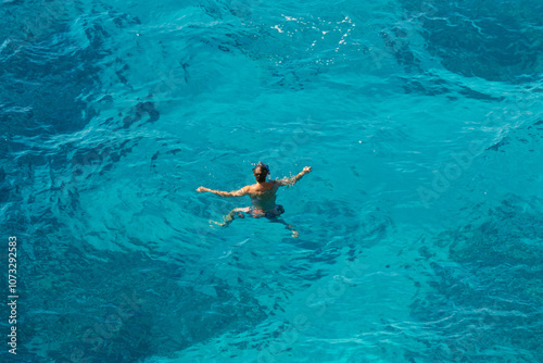 A lone man swimming in crystal-clear turquoise water, Ionian Sea, Himare, Albania, summer, filikuri beach