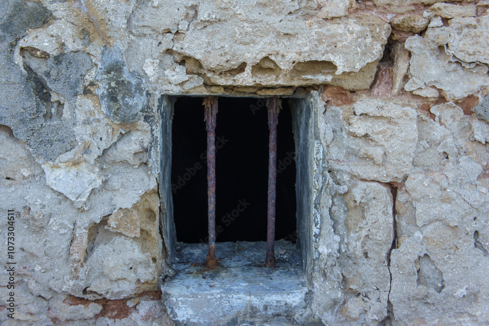Old stone prison window with rusty bars in a historic building. Old stone prison window with rusty bars in a historic building.