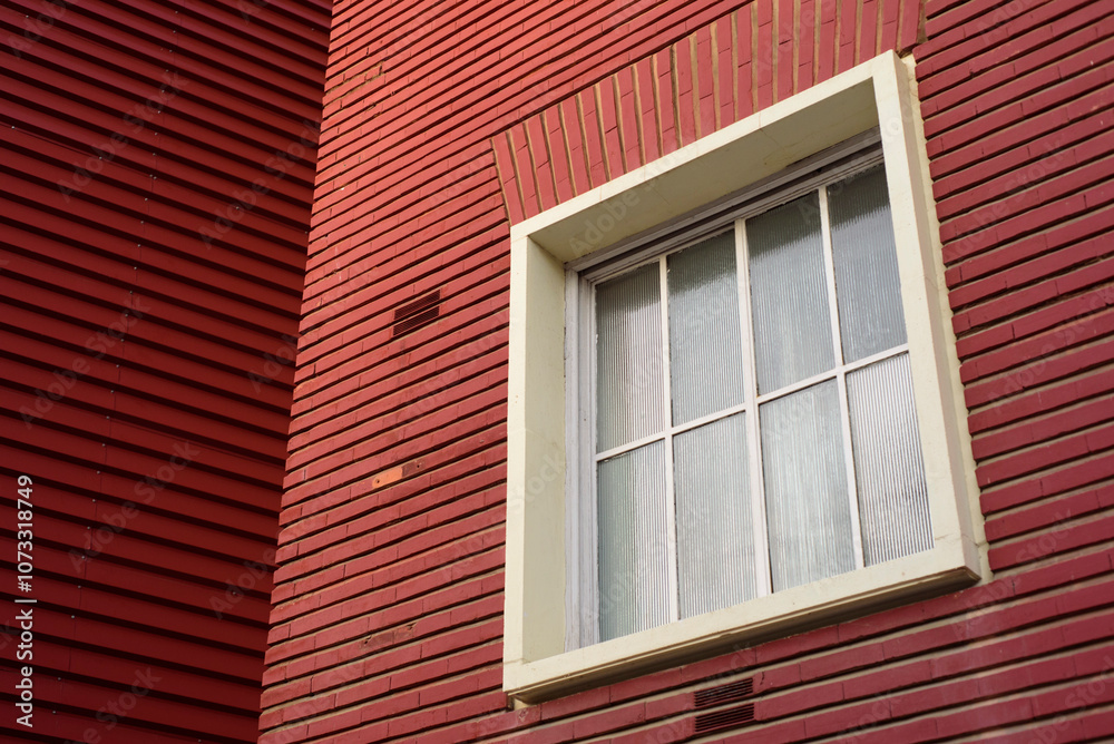 Ventana blanca en fachada de ladrillos rojos 