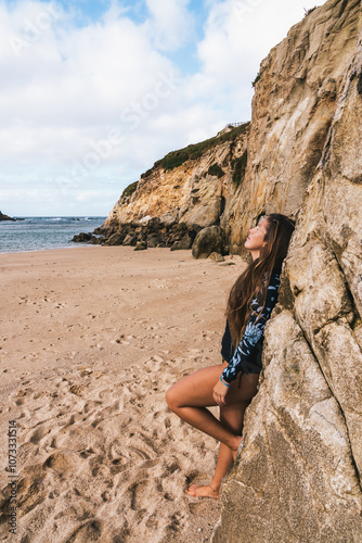 Young woman relaxing on a rocky beach in winter sunlight. Calm and connection with nature photo