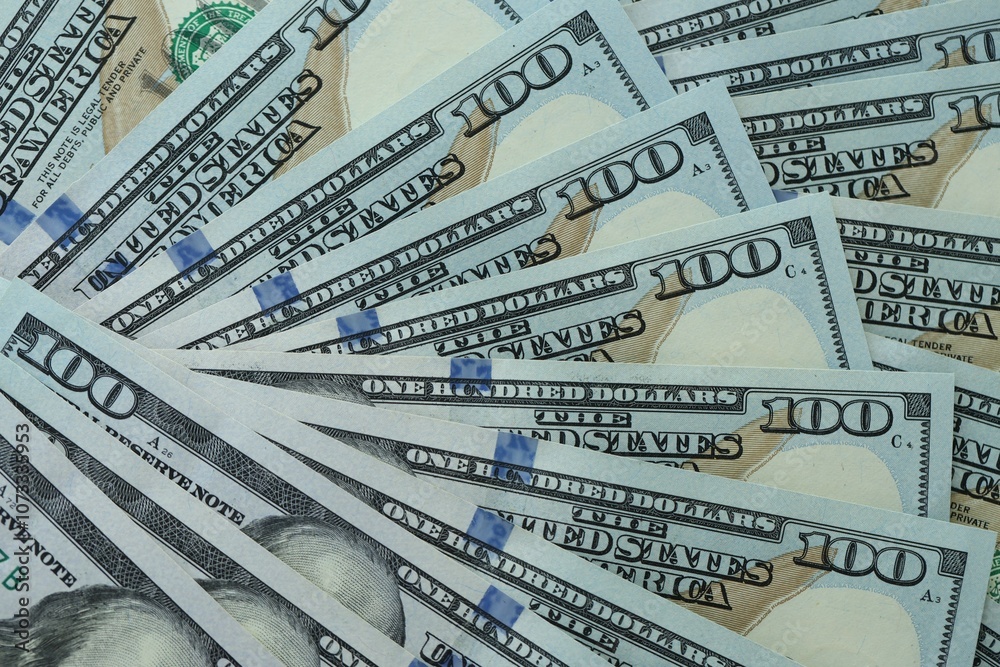 Many hundred dollar bills new banknotes in big pile under the natural light Many hundred dollar bills new banknotes in big pile under the natural light