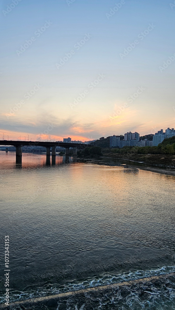 Obraz premium 서울의 한강에서 노을지는 하늘과 불빛이 반짝이는 교량이 있는 도시 경관