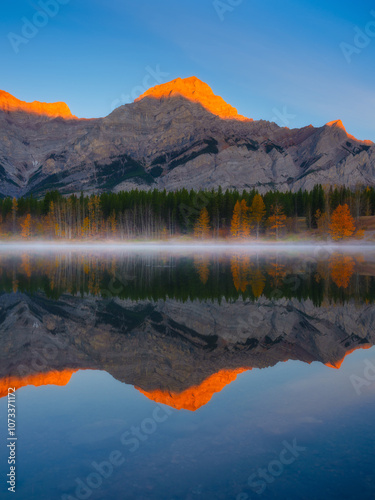Mountain landscape at dawn. Sunbeams in a valley. Lake and high peaks in a mo...