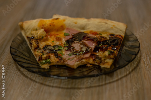 A bitten portion of pepperoni pizza on a plate on a wooden board. photo