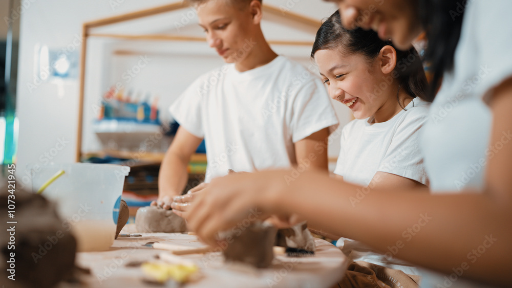 Handsome student dipping hand in to water to soften clay at art classroom. Group of diverse children working or modeling vase. Happy boy put water to young girl while laugh with happy. Edification. Handsome student dipping hand in to water to soften clay at art classroom. Group of diverse children working or modeling vase. Happy boy put water to young girl while laugh with happy. Edification.