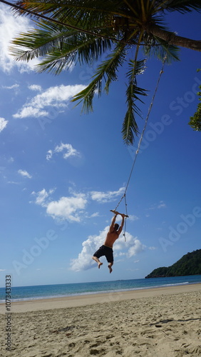 Guy on a rope swing under the palm trees in Australia