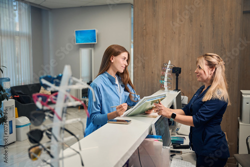 Obraz na płótnie Patient and receptionist discussing paperwork at the counter w salonie