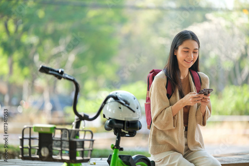 A woman is sitting on a bench with a bicycle and a helmet next to her
