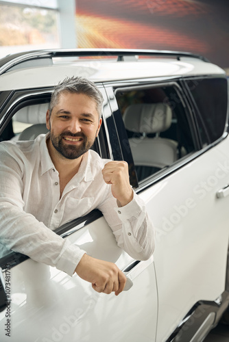 Happy man holding key, buying new car while celebrating