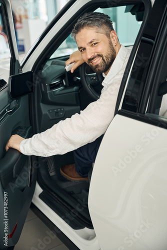 Smiling adult man buying new car, looking at camera photo