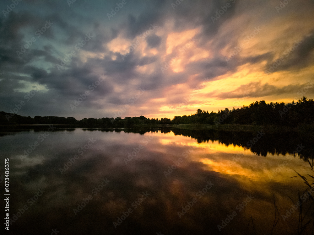 Fototapeta premium Sonnenunterng am See mit dramatischen Himmel 