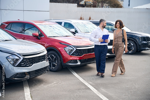 Obraz na płótnie Female client talking with salesman manager at car salon showroom outdoors w salonie