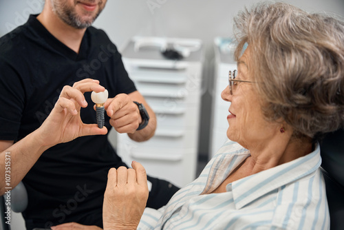 Obraz na płótnie Patient examines model of dental implant in hands of dental prosthetist w salonie