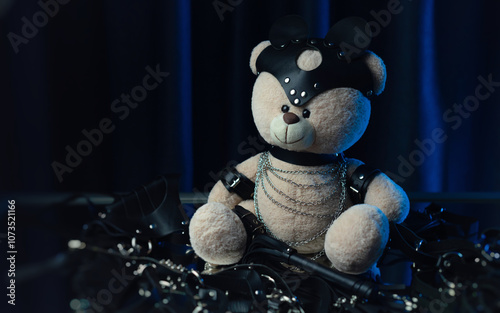 Cute toy bear in a leather belt and accessories for BDSM games on dark background in neon light