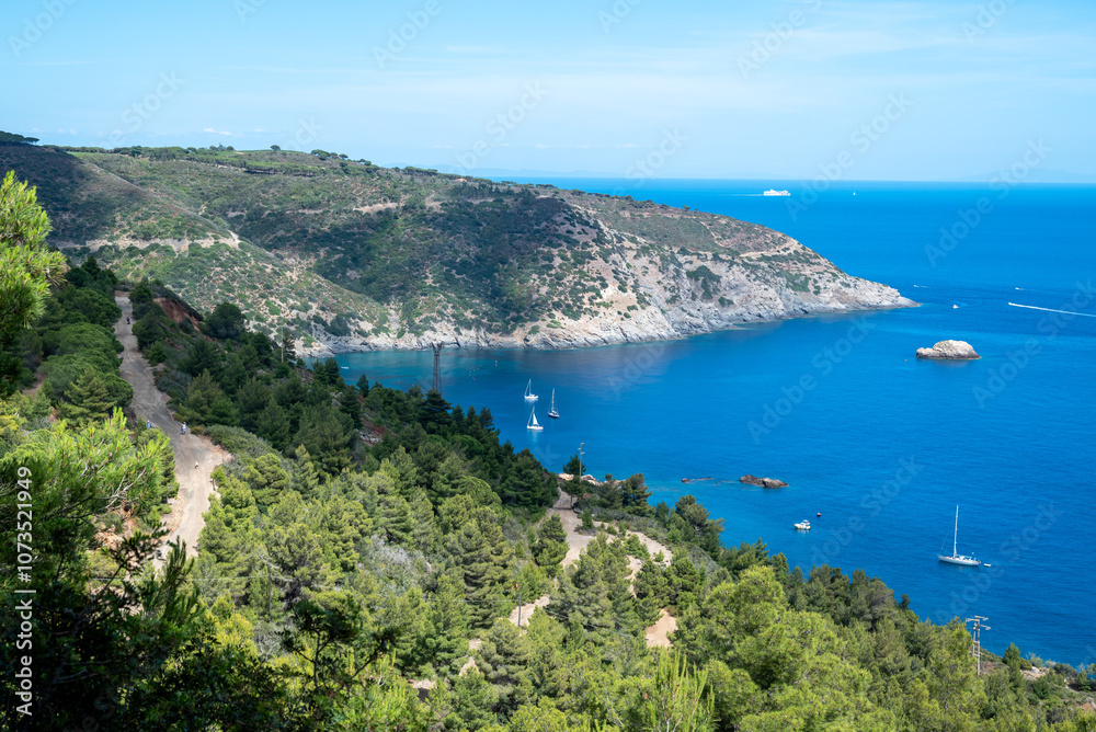 Panoramic view of the Magnet mount, a magnetite deposit where the famous iron mines of Elba island are located with yacht and sailboats on the fresh blue waters of the cape cod named Capoliveri Panoramic view of the Magnet mount, a magnetite deposit where the famous iron mines of Elba island are located with yacht and sailboats on the fresh blue waters of the cape cod named Capoliveri