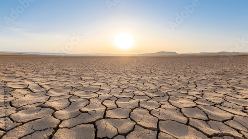Vast cracked and parched earth field with no vegetation visible and the sun low in the sky casting long dramatic shadows across the desolate scorched landscape