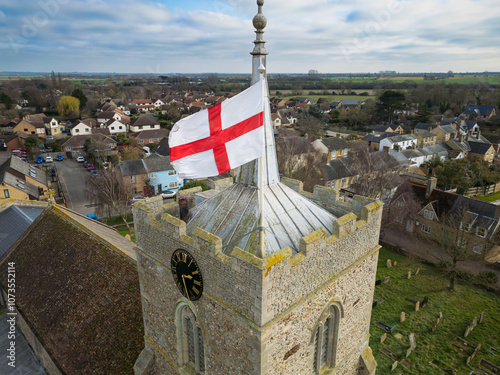 Drone view of a large St Georges flag flying in the wind at the top of a bell tower of a typical English church. photo