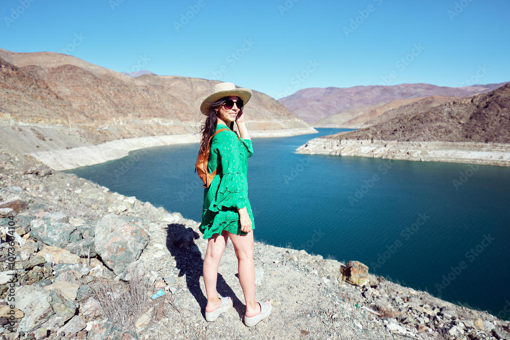 Naklejka premium Beautiful latin tourist woman posing outdoors in the Huasco valley with a damn in the background