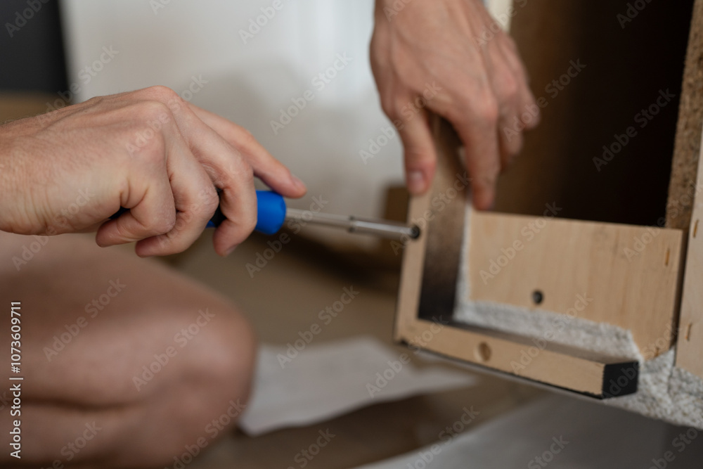A man is assembling a sofa by himself at home. close up hands with screwdriver A man is assembling a sofa by himself at home. close up hands with screwdriver