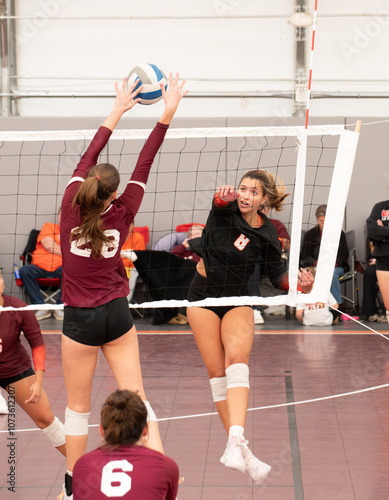 Female college volleyball player getting blocked by a single right side blocker