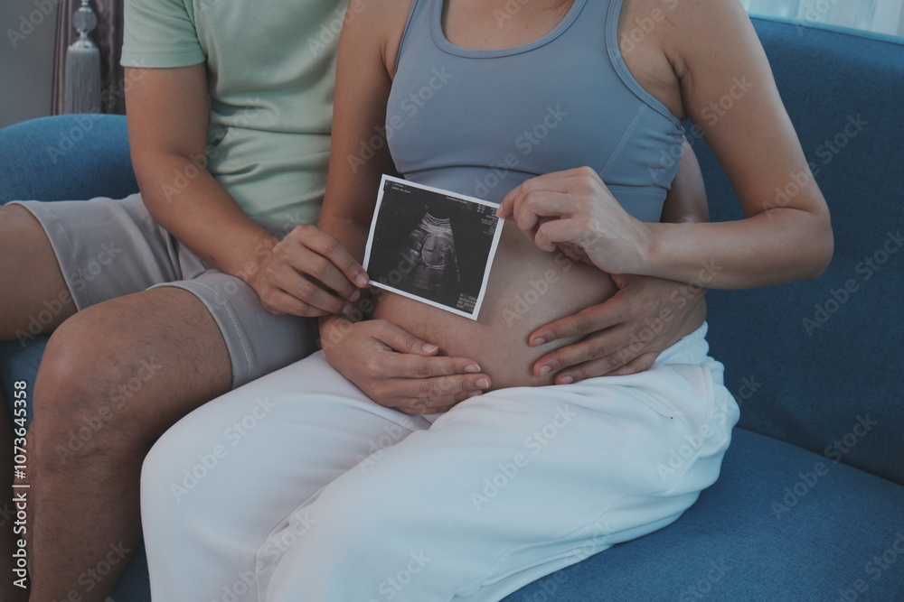 The hands of the pregnant parents hold the seven-month pregnant mother's belly to show the results of the fetal examination in the womb.