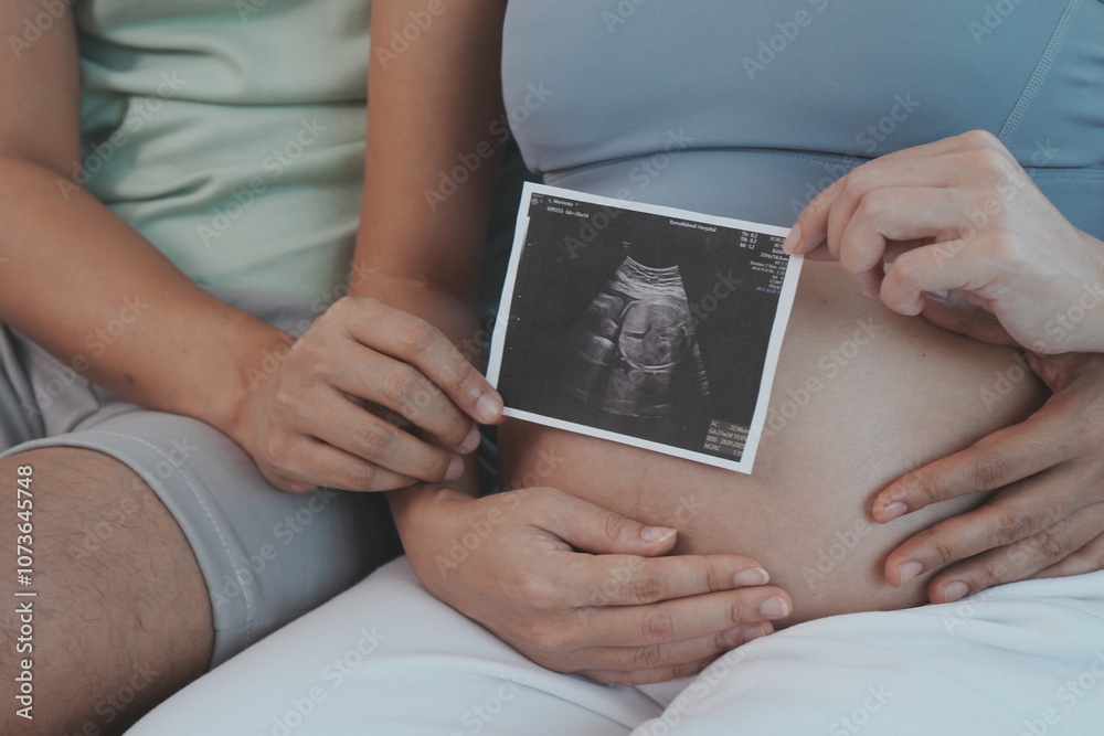 The hands of the pregnant parents hold the seven-month pregnant mother's belly to show the results of the fetal examination in the womb.