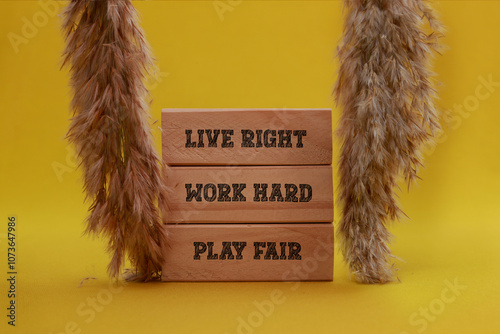 Live Right work hard play fair written on wooden blocks with yellow background. Inspirational Words. Conceptually ideal way to live even for businesses and leaders