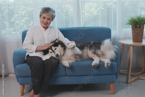 Obraz na płótnie Senior Asian woman sitting on sofa relaxing with Siberian Husky playing with pet happy w salonie