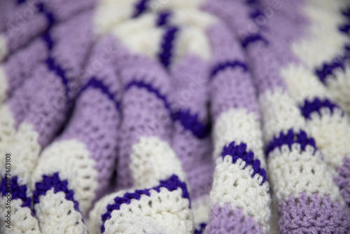 close-up of grandma's retro zigzag striped blanket, in white, lilac or lavender and royal purple, crocheted or knitted, grandma's house, cozy and warm, rippling photo