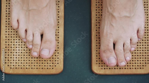Close-up of feet on a wooden acupressure sadhu board outdoors, providing natural foot therapy and relaxation.