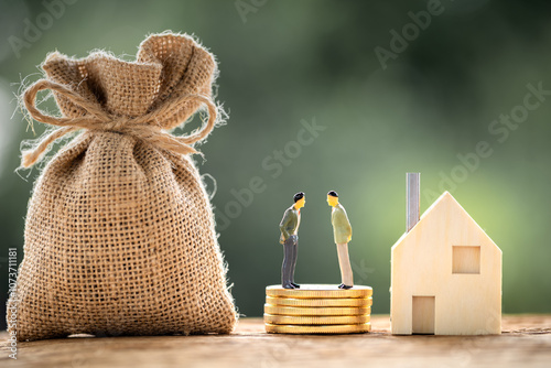 Two businessmen standing on the stack coins are negotiating for buy and sell or exchange purchase a home and money bag put on the wood in the public park, Loan and investment for real estate concept. photo