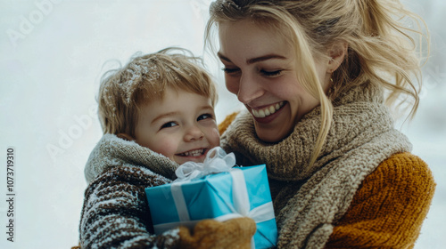 Smiling caucasian mother and son gift giving in snowy winter outdoors