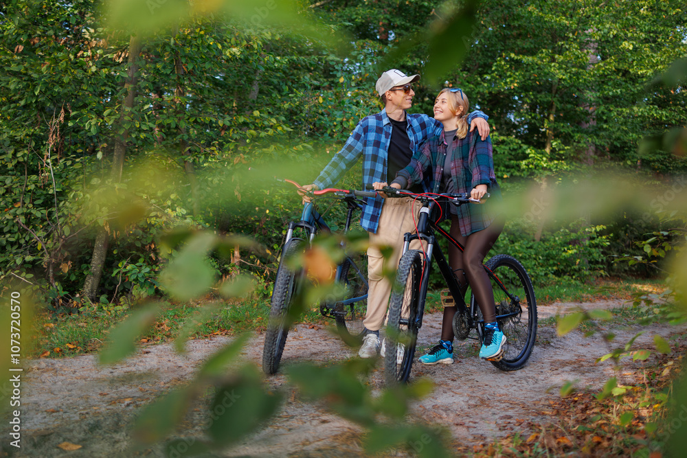 Obraz premium A young man hugs a girl while standing in nature while riding a bike
