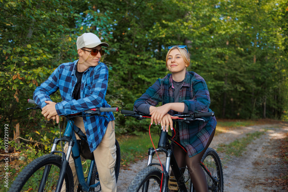 Obraz premium Happy young couple enjoying cycling through the forest
