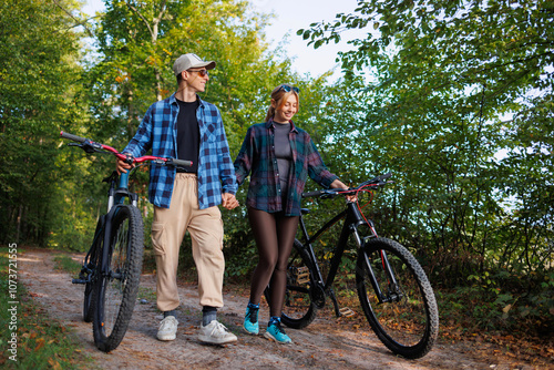 Young man and a woman walk in nature with bicycles after riding