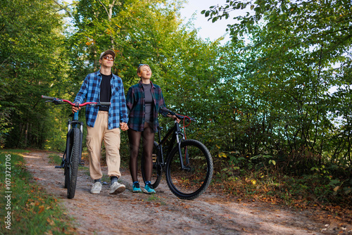 Young man and a woman walk in nature with bicycles after riding