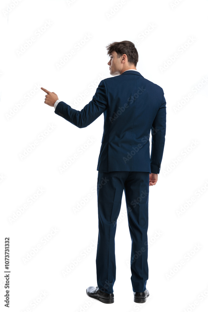 behind view of young businessman showing to side by pointing finger behind view of young businessman showing to side by pointing finger
