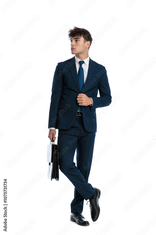 attractive young man with suitcase looking to side and buttoning suit attractive young man with suitcase looking to side and buttoning suit